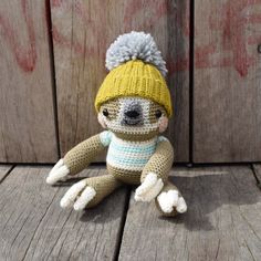 a small stuffed animal wearing a knitted hat and scarf sitting on a wooden floor