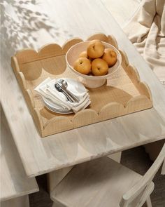 a bowl of apples is sitting on a wooden tray with silverware and napkins