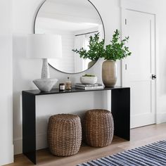 a black table with two stools and a round mirror on the wall above it