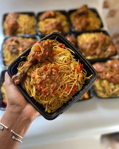 a person holding up a plate of spaghetti with meat and sauce on it in front of muffins