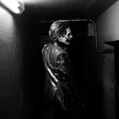 a man in a leather jacket is standing in a dark room with his head turned to the side