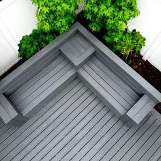 an overhead view of a wooden deck in front of some bushes and shrubbery on the side of a house