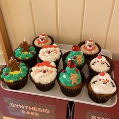 cupcakes decorated with santa claus and snowmen on top of a red box