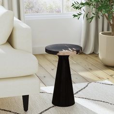 a living room with white furniture and a potted plant on the floor next to it