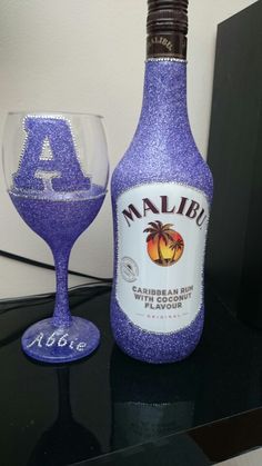 a purple wine bottle next to a glass on a table