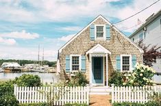 a house with blue shutters next to a white picket fence in front of it