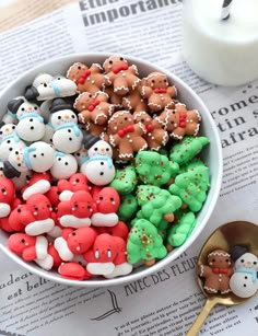 a bowl filled with christmas cookies next to a cup of milk on top of a newspaper