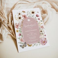 a pink and white floral graduation party card on top of a cloth covered tablecloth