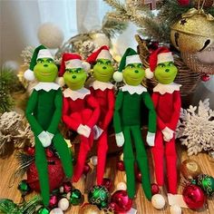 three green and red christmas elfs standing next to each other in front of a christmas tree