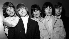 the rolling stones posing for a photo in front of a wall with their heads tilted