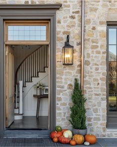 pumpkins and gourds sit on the front steps of an old stone house