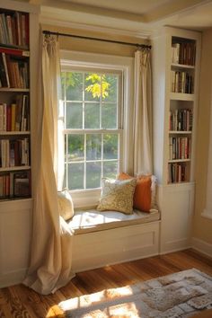 a window seat in front of a book shelf filled with books