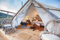 the interior of a tent with chairs and tables in it on a wooden floor next to a bed