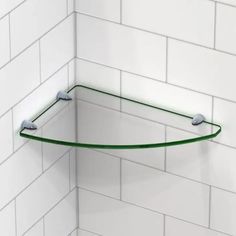 a curved glass shelf in the corner of a white tiled shower stall with green trim