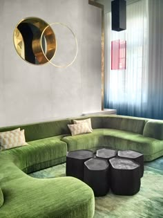 a living room filled with green couches and round tables