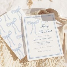 two wedding cards with bows on them sitting on a lace tablecloth next to ribbons