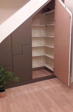 an empty closet in the corner of a room next to a potted plant and stairs