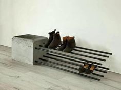 four pairs of shoes are sitting on a metal rack in front of a white wall