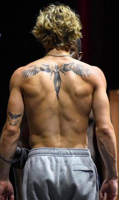 the back of a man with tattoos on his upper and lower half, showing an eagle