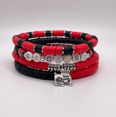 Show your team pride with our set of 4 red and black game day stackable bracelets. Each handmade bracelet is made from polymer clay heishi discs on stretch beading thread and finished with silver plated bulldog or football charm. Georgia Bulldogs Clay Bead Bracelet, Red Stacked Beaded Bracelets For Gifts, Red Stacked Beaded Bracelets As Gift, Adjustable Red Stackable Beaded Bracelets, Red Adjustable Stackable Beaded Bracelets, Adjustable Stackable Red Beaded Bracelets, Black Beaded Bracelets With Letter Beads For Game Day, Red Adjustable Stacked Bracelets, Red Heishi Beads Jewelry With Letter Beads