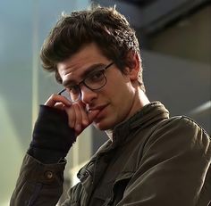 a young man wearing glasses is looking at his cell phone