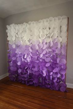 purple and white flowers are hanging on the wall in front of a wooden flooring area