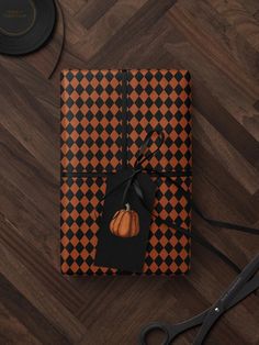 an orange and black checkered wrapping paper with a pumpkin on it next to scissors