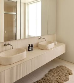 a bathroom with two sinks, mirrors and a rug in front of the sink area