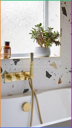 a bathtub with a plant in it next to a mirror and other bathroom accessories