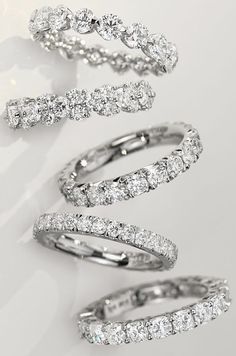 three different types of diamond rings on a white surface with one ring in the middle