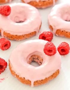 raspberry donuts with icing and fresh raspberries on the side