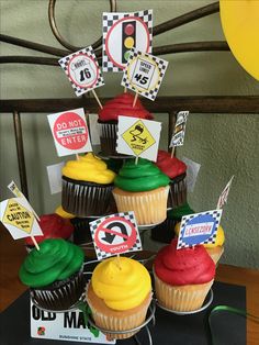 cupcakes with colorful frosting and signs on them are arranged in a tower