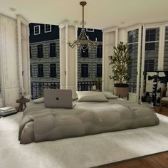 a computer is sitting on top of a bed in a room with windows and a chandelier