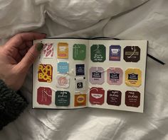 a person is holding an open book with stickers on it and the pages are covered in different colors