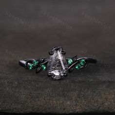 an unusual ring with green crystal stones on it's sides, sitting on a rock