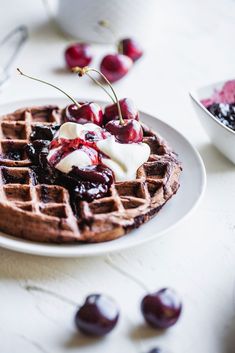 a waffle topped with whipped cream and cherries