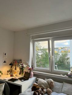 a living room filled with furniture and a large window next to a desk topped with a laptop computer