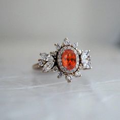 Immerse yourself in a world of timeless beauty with our Coco Fanta Orange Spessartite Garnet Coco Diamond Ring, a true testament to class and elegance. This ring seamlessly combines the grace of marquise and round diamonds, elevating the sense of style on the wearer. A proportionately beautiful design with a touch of vintage charm, it features a natural vivid Orange Spessartite adorned with the brilliance of natural white diamonds. Handcrafted with precision, this ring is available in 14K and 18K yellow gold, rose gold, and white gold. Only one available. Spessartite/Spessartine is known for its fiery red-orange color, hence why it's called the "Garnet of the sun". Spessartine garnet is a stone known for positive emotions and creativity. It encourages a rational state of mind, emotional st Fanta Orange, Spessartine Garnet, Red Orange Color, Spessartite Garnet, Fiery Red, Positive Emotions, Marquise Diamond, The Grace, White Diamonds