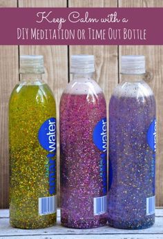 three bottles filled with glitter sitting on top of a wooden table next to each other