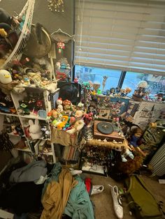 a room filled with lots of clutter and stuffed animals on the floor next to a window