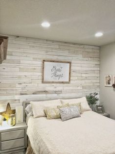 a white bed sitting in a bedroom next to a wall with a wooden sign above it