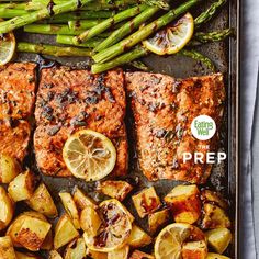 salmon and asparagus on a baking sheet with lemons, potatoes and asparagus