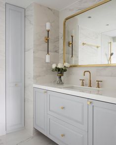 a white bathroom with marble counter tops and gold accents