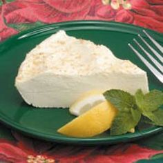 a piece of cheesecake on a green plate with lemon wedges and mint leaves