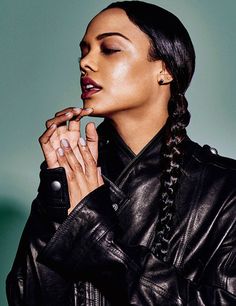 a woman in black leather jacket holding her hands to her mouth and looking off into the distance