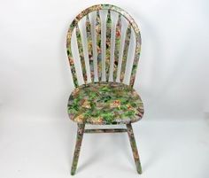 a wooden chair with floral fabric on it's back and seat, against a white background