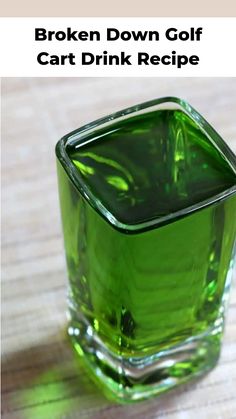 a green glass filled with liquid sitting on top of a wooden table