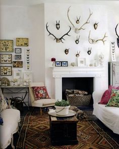 a living room filled with furniture and lots of antlers on the wall above it