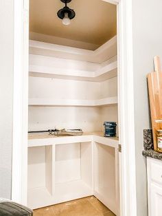 an empty pantry with white cabinets and wood flooring