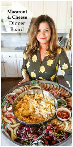 a woman standing in front of a platter of food with the words macaroni and cheese dinner board